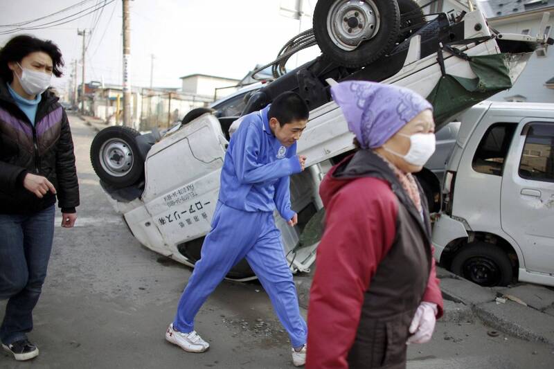 2011年311大地震後，青森縣的居民行經遭受海嘯及地震襲擊的車輛，示意圖。（路透）