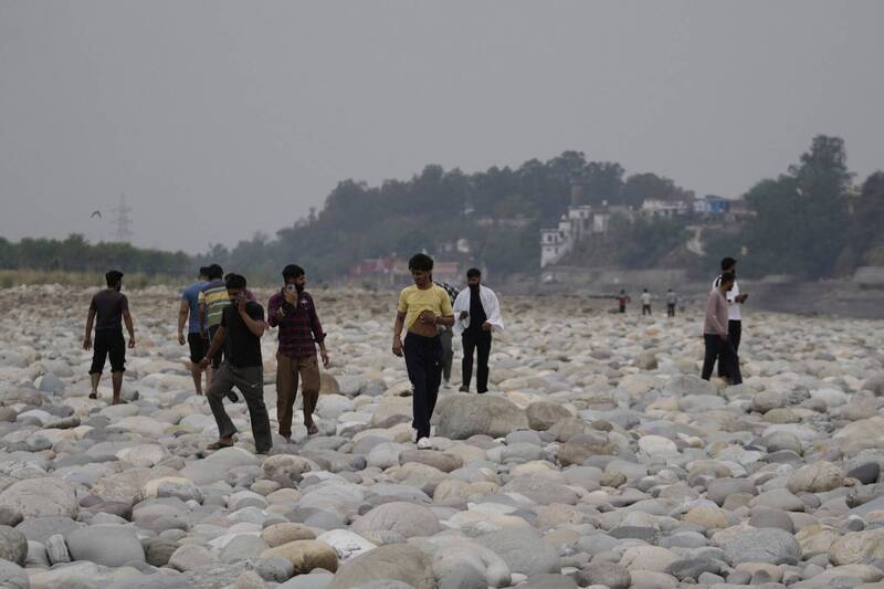 印度查謨郊區一座水壩斷水後，人們穿過乾涸的奇納布河。（美聯社）