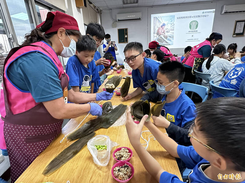 台南新市國小畢業班學童跟著新市區農會家政班媽媽學包粽,在地毛豆入粽。(記者劉婉君攝) 台南新市國小畢業班學童跟著新市區農會家政班媽媽學包粽,在地毛豆入粽。(記者劉婉君攝)