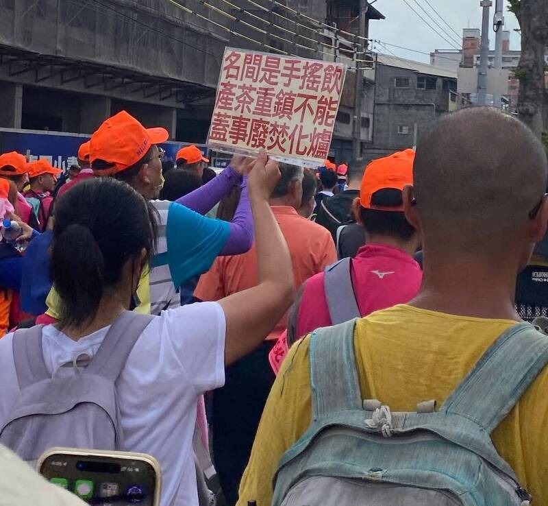 白沙屯媽祖在南投名間鄉遶境時，有民眾手持「名間是手搖飲產茶重鎮不能蓋事廢焚化爐」標語牌，引發關注。（民眾提供）