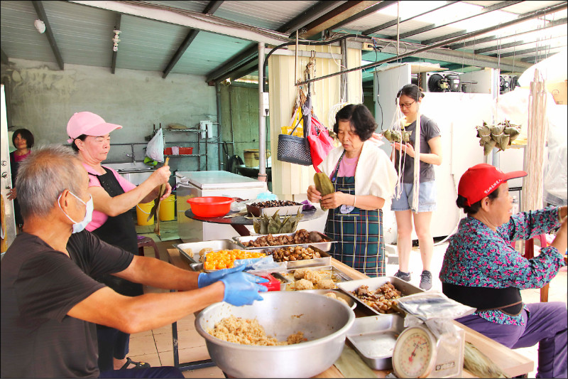 新竹縣寶山鄉新城村「東坑口」地區住戶，在謝姓善心人號召下，由鄉親鄧鳳英（左，戴帽者）帶領，每年端午節跟尖石、五峰的偏遠原鄉有三千顆粽子之約。昨天志工夥伴出動一起包粽，這已是第四波包粽行動，最多時一度有卅幾人共同「出手」，就為週六（廿四日）能如期送上山，分享給家境弱勢原鄉朋友也能吃到美味溫暖的客家粽。（圖文：記者黃美珠）