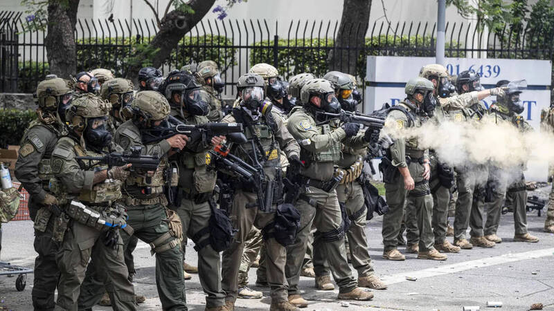 美國邊境巡邏隊人員6月7日在加州派拉蒙市向抗議民眾施放催淚瓦斯,現場煙霧瀰漫。此前一天,聯邦移民當局在此地進行大規模逮捕行動。(美聯社) 美國邊境巡邏隊人員6月7日在加州派拉蒙市向抗議民眾施放催淚瓦斯,現場煙霧瀰漫。此前一天,聯邦移民當局在此地進行大規模逮捕行動。(美聯社)