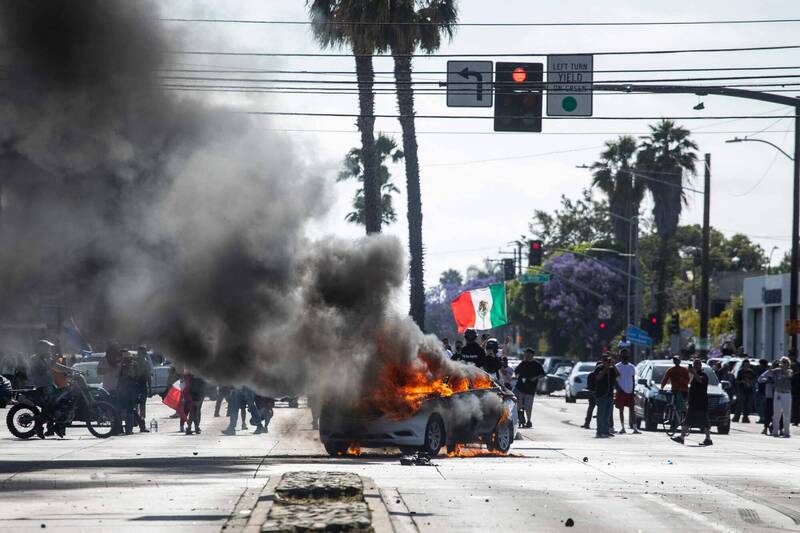 美國洛杉磯康普頓(Compton)地區6月7日爆發激烈抗議,一輛汽車在示威中遭焚燒。事件起因於聯邦移民當局的掃蕩行動。(法新社) 美國洛杉磯康普頓(Compton)地區6月7日爆發激烈抗議,一輛汽車在示威中遭焚燒。事件起因於聯邦移民當局的掃蕩行動。(法新社)