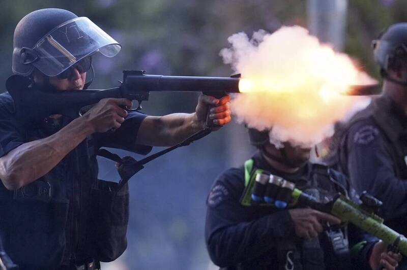 美國洛杉磯市中心大都會拘留中心附近,一名警員於8日向抗議移民執法行動的示威者發射非致命彈藥。此前一晚當地已爆發激烈警民衝突。(美聯社) 美國洛杉磯市中心大都會拘留中心附近,一名警員於8日向抗議移民執法行動的示威者發射非致命彈藥。此前一晚當地已爆發激烈警民衝突。(美聯社)