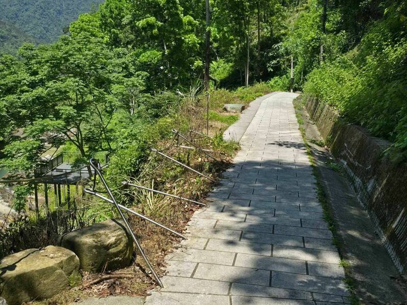 萬年峽谷水泥步道旁拉繩的白鐵桿整排傾倒。（民眾提供）