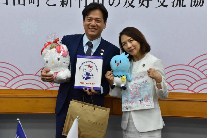 新竹市代理市長邱臣遠（左），與三麗鷗主題樂園營運公司社長小卷亞矢（右）交換當地紀念品。（西日本新聞提供）