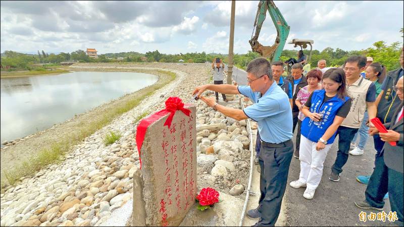 嘉南管理處主任林連文以水澆淋虎頭埤堤防修建碑，象徵飲水思源。（記者劉婉君攝）