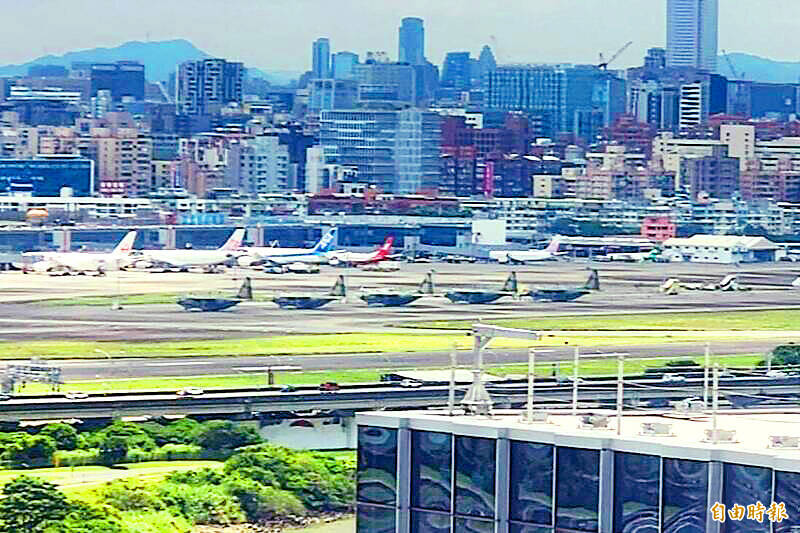 Air force C-130s, front row, and civilian airliners, back row, are pictured at Taipei International Airport （Songshan airport） yesterday. The military cargo transports were flown from Pingtung Air Base to take shelter ahead of approaching Tropical Storm Danas.
Photo: Liu Yu-chieh, Taipei Times