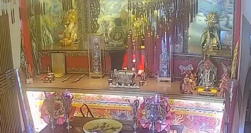 罗嫌顺著供桌爬上，伸手取下金牌并塞进衣中。（记者刘人玮翻摄）