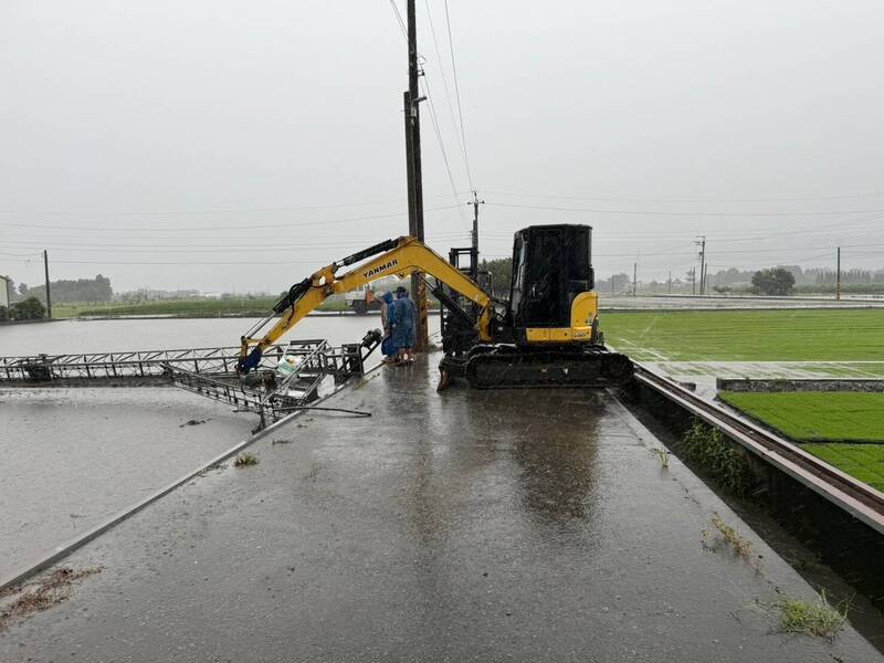 人力加上機械幫忙，農民要把被吹翻的秧苗機轉正。（陳翰立提供）