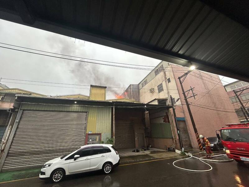 桃園市平鎮區平東路1間鐵皮加蓋的塑膠射出工廠，今晨2樓不明原因起火燃燒，竄起濃煙。（記者黃政嘉翻攝）