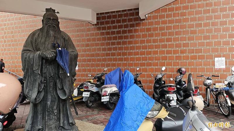 彰化縣圖廣場的孔子像淪為雨傘架。(記者劉曉欣攝) 彰化縣圖廣場的孔子像淪為雨傘架。(記者劉曉欣攝)