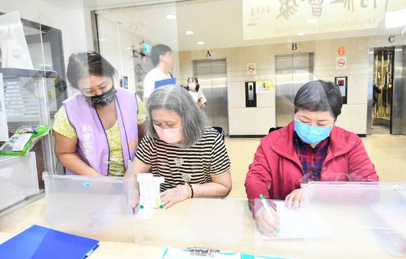 民眾在彰化縣政府社會處「臨櫃製卡站」現場填寫長青卡申請資料,志工協助說明。(社會處提供) 民眾在彰化縣政府社會處「臨櫃製卡站」現場填寫長青卡申請資料,志工協助說明。(社會處提供)