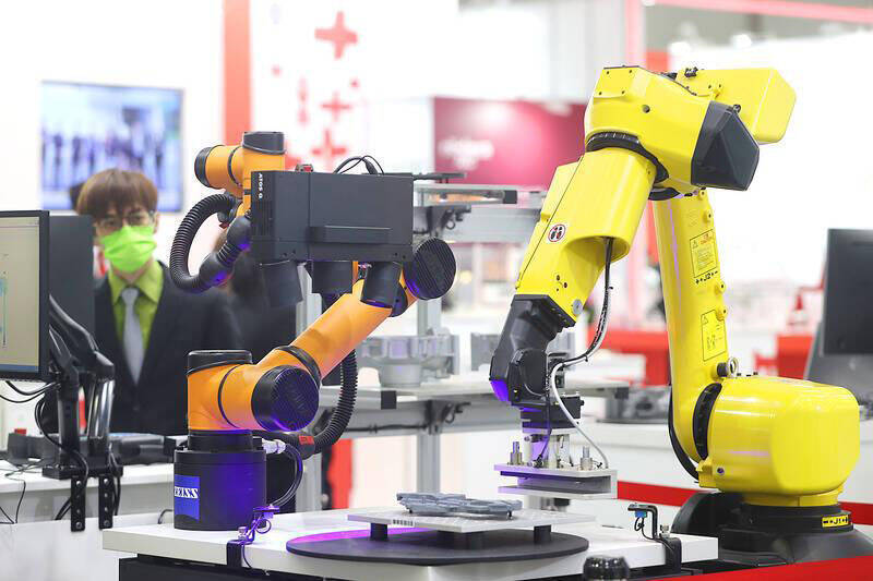 
A visitor looks at robotic arms displayed at the Taipei International Machine Tool Show at the Taipei Nangang Exhibition Center’s Hall 1 on March 6, 2023.
Photo: CNA