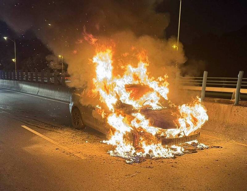 整輛轎車被大火吞噬，烈焰照亮夜空。（圖由消防局提供）