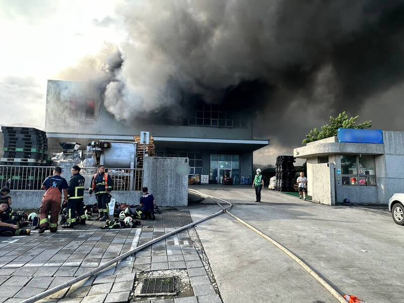新北市八里一處食品廠堆放的食品原料起火竄出濃煙，消防隊灌救中。（記者吳仁捷翻攝）