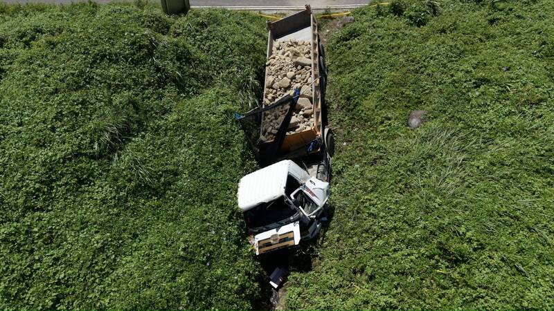 砂石車與小客車對撞後衝出護欄，翻落外海岸邊礁石處，40歲砂石車受困車底當場死亡。（記者林嘉東翻攝）