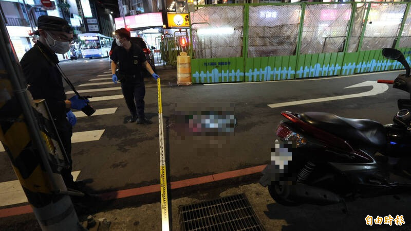 警方鑑識人員於財神大樓前人孔蓋採證。（記者黃政嘉攝）