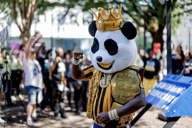 圖為喬治亞州亞特蘭大的示威現場，一名抗議者身著奇特的熊貓裝，高舉拳頭表達訴求。（歐新社）