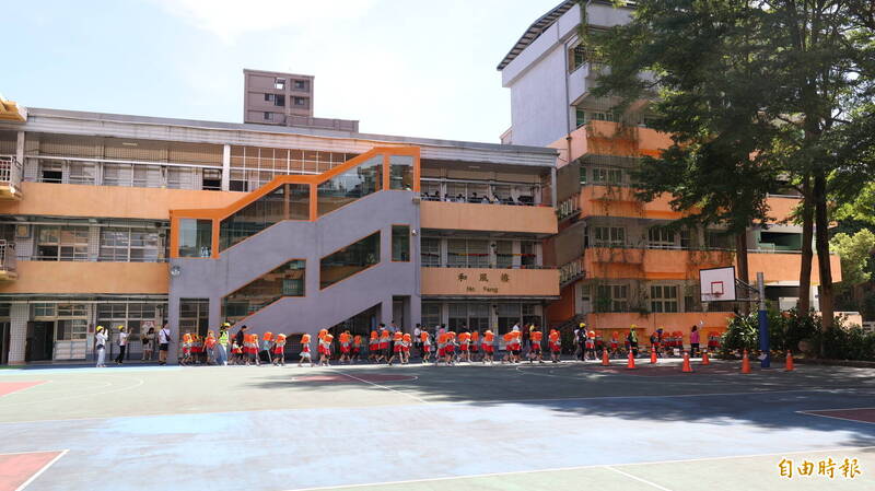 新北市頂埔國小1000位師生在地震警報聲響起後，戴著防災頭套至操場避難。（記者黃政嘉攝）