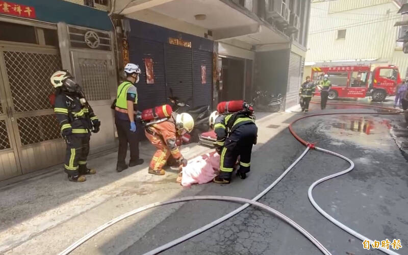 消防隊員搜救發現一男子全身焦黑，已無生命跡象，將其用布袋扛出。（記者陳冠備攝）