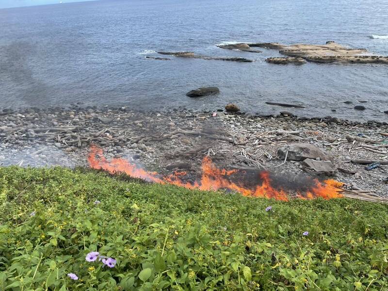 新北市瑞芳區員山子分洪道出水口草叢今天上午傳出火警。新北市消防局獲報馳援，引海水灌救，迅速撲滅火苗，仍有餘燼未滅，消防員持續滅火中。（記者林嘉東翻攝）