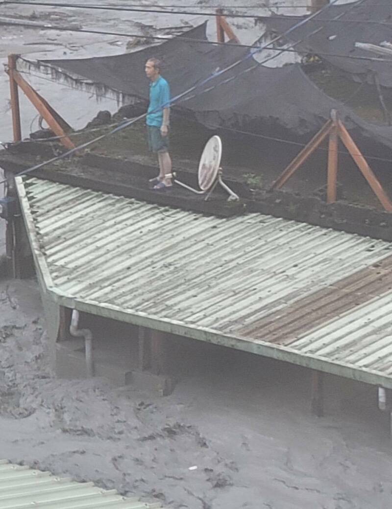 大水來時來不及跑，居民爬到屋頂等待救援。（民眾提供）