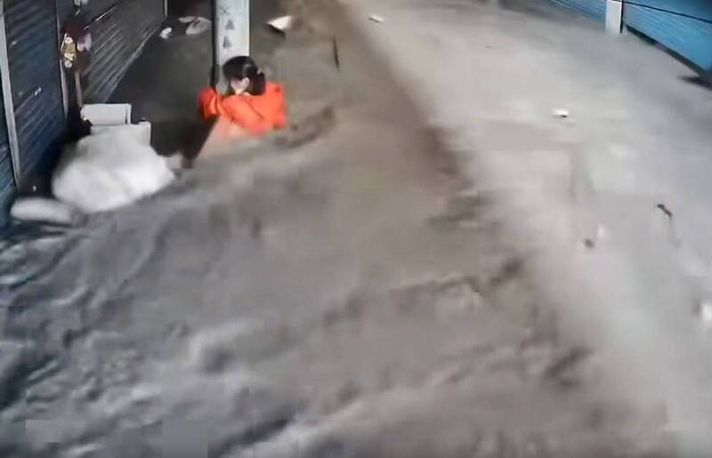 光復鄉市場已遭泥水淹沒，監視器畫面顯示，下午4點許有婦人在湍急的泥流中緊抱電線桿待援。（圖擷自網路）