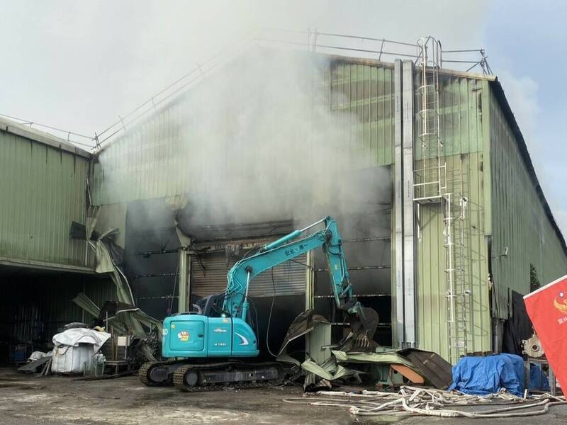 廠內堆置大量木屑，雲林縣消防局持續以挖土機開挖處理殘火中。（雲林縣消防局提供）