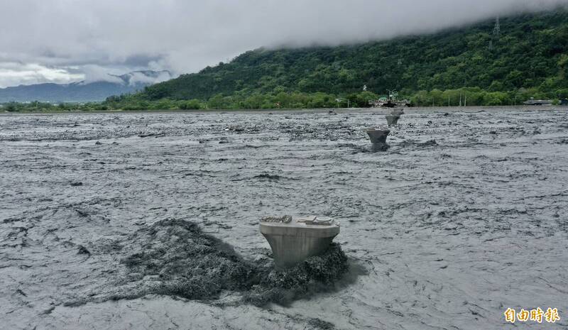馬太鞍溪橋被溢流沖毀，剩橋墩孤立在黑色洪流中。（記者羅沛德攝）