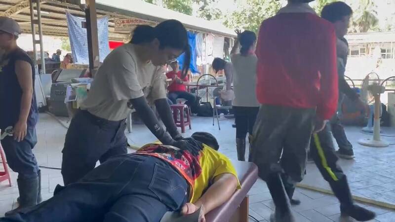 志工在光復糖廠物資站替前線人員進行背部推拿，讓鏟土與搬運後肌肉痠痛的志工與國軍，獲得舒緩與體能恢復。（愛吃輝提供）