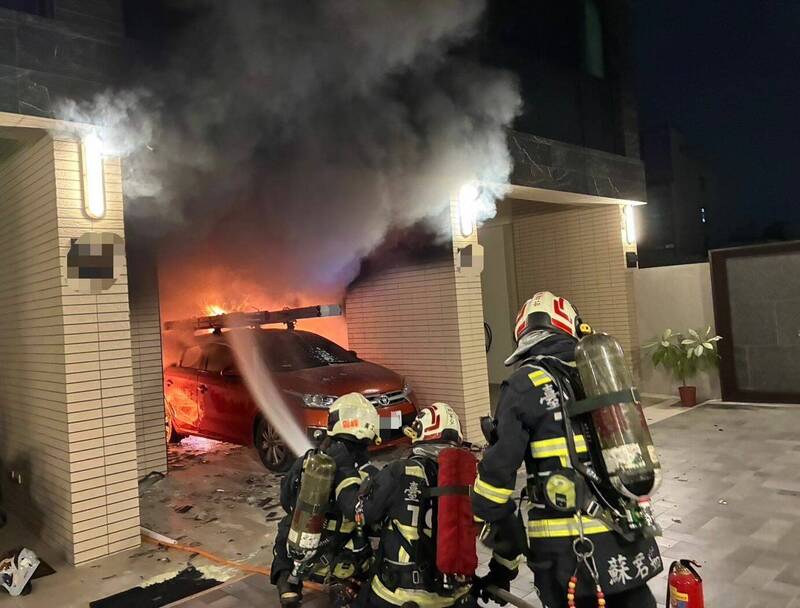 台中大里美群路194巷一處民宅車庫今晚起火，現場火苗、濃煙直竄，消防人員出水搶救。（記者陳建志翻攝）