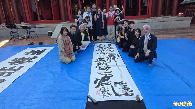 日本書法家與陳世憲作品「喜極而起舞，隱約的認出前進的路痕」合影。（記者洪瑞琴攝）