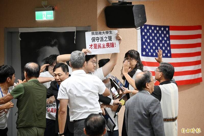 自稱政大學生突襲舉牌抗議應邀在「查理•柯克紀念會」致詞的台聯黨主席周倪安。（記者陳逸寬攝）