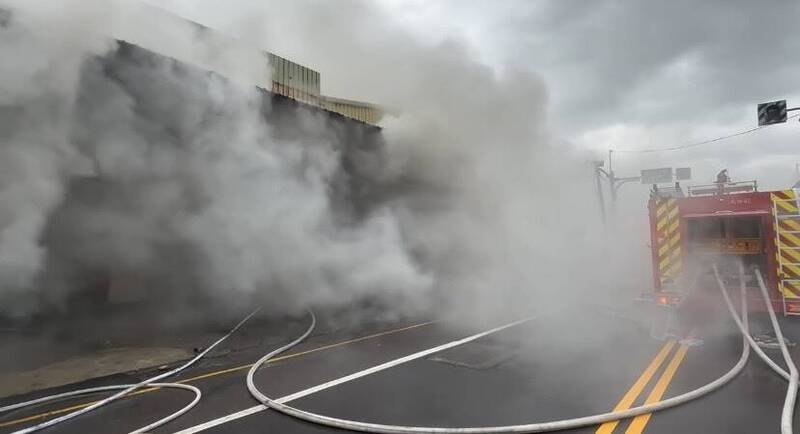 桃园市桃园区树仁三街今早惊传仓库火灾，浓烟密布，场内疑有1男1女员工受困，消防单位射水灭火并搜救人员。（图由桃园市消防局提供）
