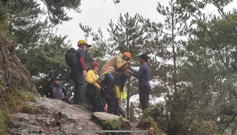 彭女因高山症发作，由警消人员背负下山。（图由警方提供）