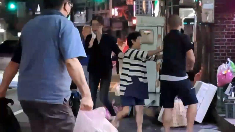 女店员被殴后，用右手扶著下巴。（记者吴升儒翻摄）