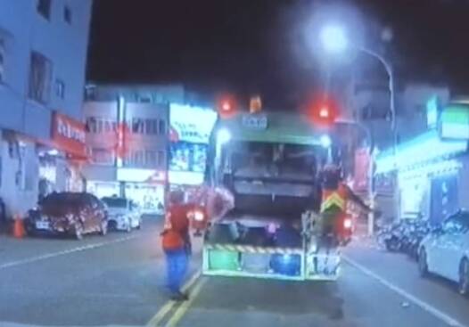 红色上衣的邱姓妇人提著垃圾穿越马路赶上垃圾车，顺利倒完垃圾。（取自《仁德生活圈》）