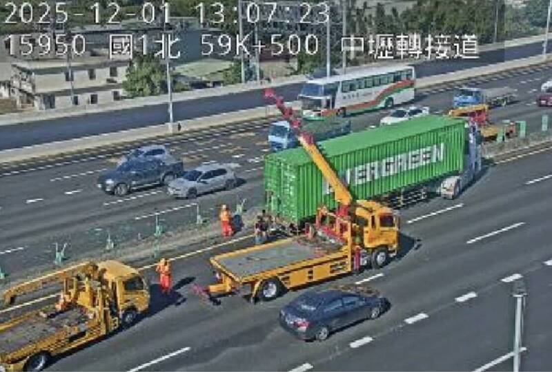 长荣货柜车行经国1中坜路段爆胎擦撞轿车、内侧护栏，国道警方通知吊车进行拖吊。（记者李容萍翻摄）