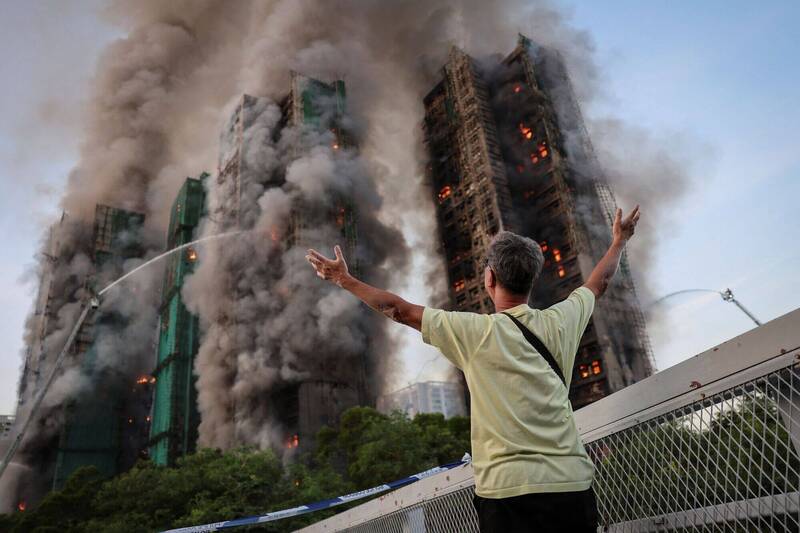 11月26日，宏福苑居民黄先生对著陷入火海的自家公寓大楼高举双臂。（路透）