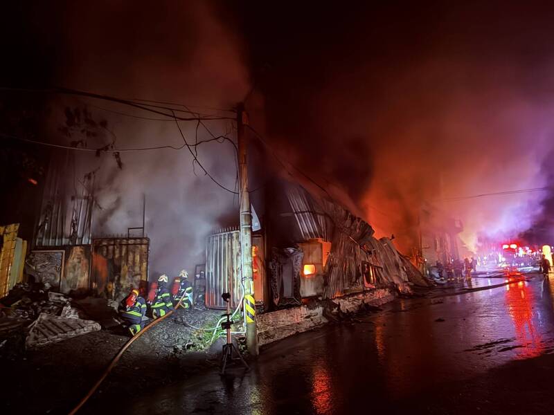 新北市八里一間木作鐵皮工廠今天凌晨失火，火勢大作，延燒燒毀三間工廠，起火原因仍待調查，新北市針對鄰近雙北四區發出空汙警戒。（記者吳仁捷翻攝）