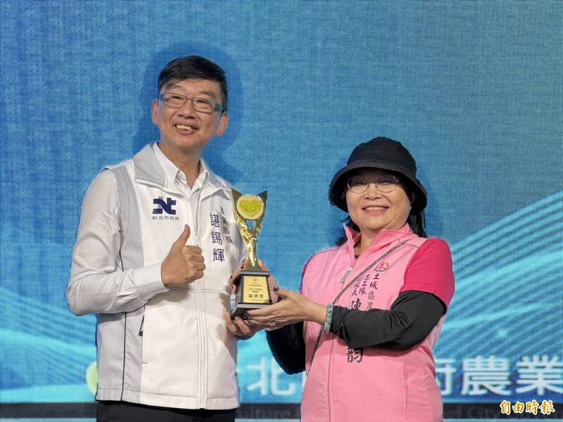 新北市農業局長諶錫輝（左）表揚獲全國志願服務獎勵銅牌獎的土城農會志工陳岫韻（右）。（記者羅國嘉攝）