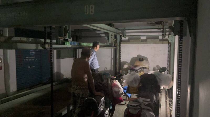 郭男寄生在大楼地下室故障的机械停车位2年多，上头堆满床舖、家当等物品，连机车都能停入。（民众提供）