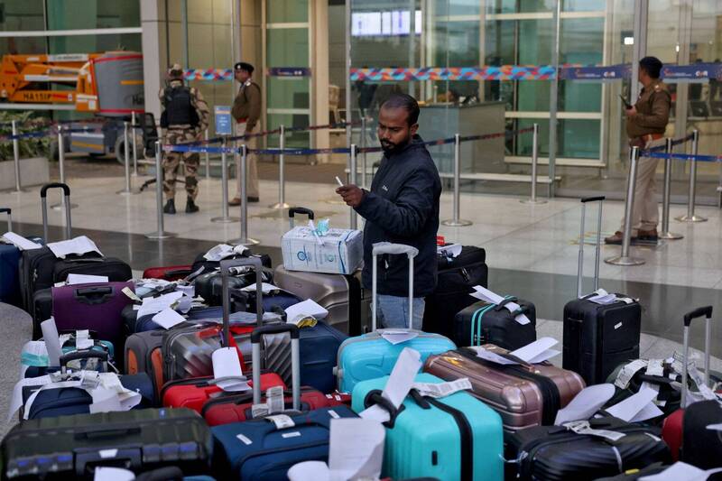 在印度新德里英迪拉甘地国际机场1号航站，一名靛蓝航空（IndiGo）工作人员正在为因大规模航班延误而滞留的靛蓝航空乘客的行李和物品贴标签。（路透）