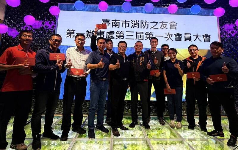 台南市消防之友會理事長蔡明憲（前排右五）頒發慰問金感謝搶救烏樹林暫置場大火的消防人員。（消防局第一大隊提供）