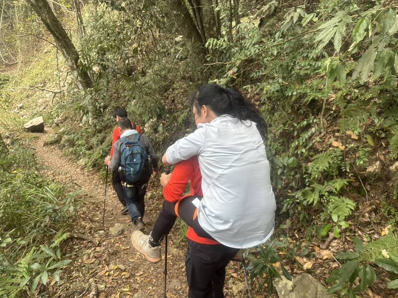 搜救人员已接触到2名被蜂螫伤的山友，并背女山友下山中。（民众提供）