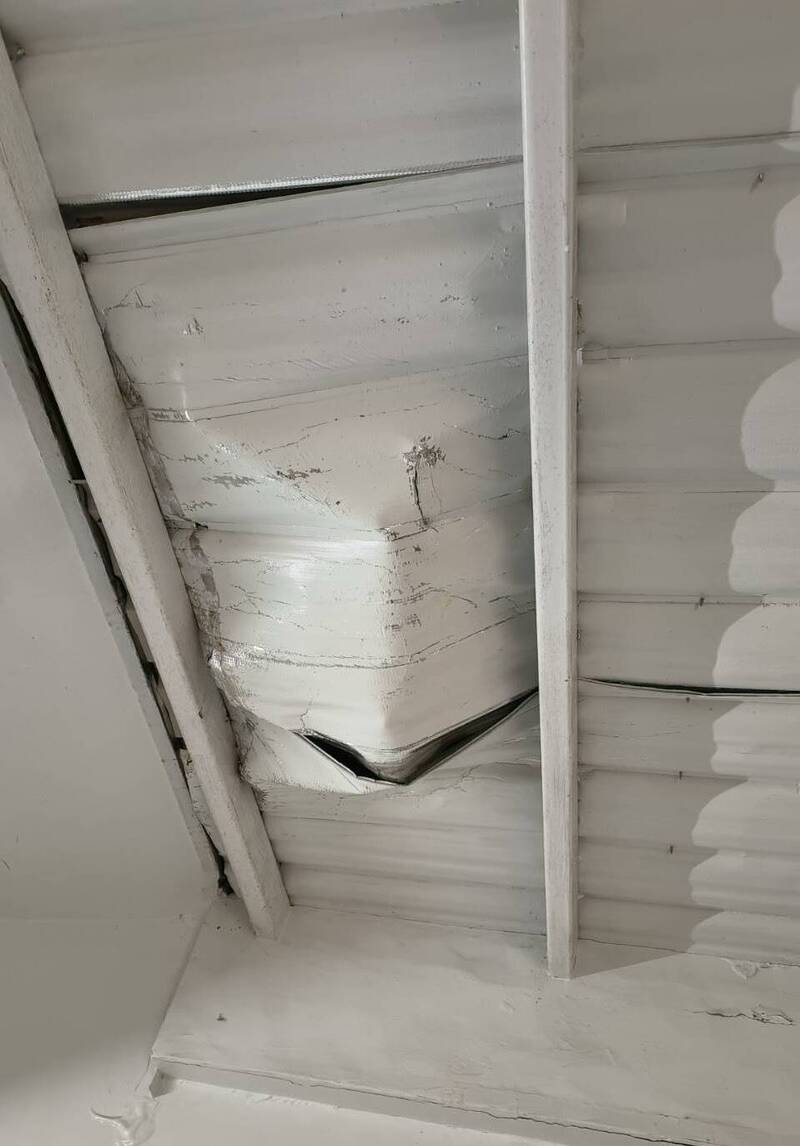 新北市板桥一处社区保全员竟跑到顶楼往楼下丢掷灭火器，造成隔壁社区铁皮屋顶毁损。（记者吴仁捷翻摄）