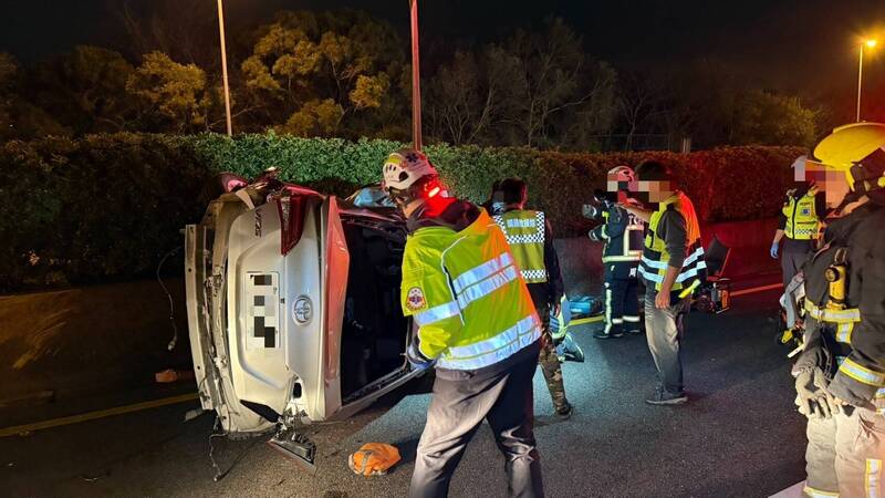 洪女駕駛的轎車被撞側翻，其與女乘客受困，警消到場救援。（民眾提供）