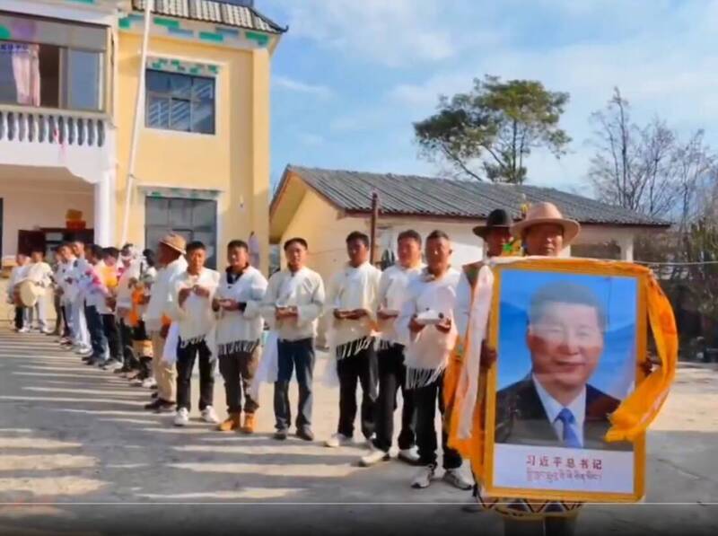 藏民身穿白衣排队，排头者手举「习近平总书记」的大幅相框。（取自萨格尔扎西SakarTashi X 影片）