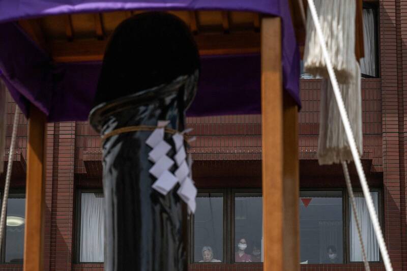 川崎市年度「金山神社生殖祭」舉行期間，巨型的男性象徵神轎穿梭街頭，吸引鄰近建築內的民眾從窗口探視。（法新社）